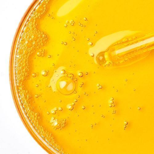 A close up of a petri dish filled with orange bubbly liquid with a pipette inside.