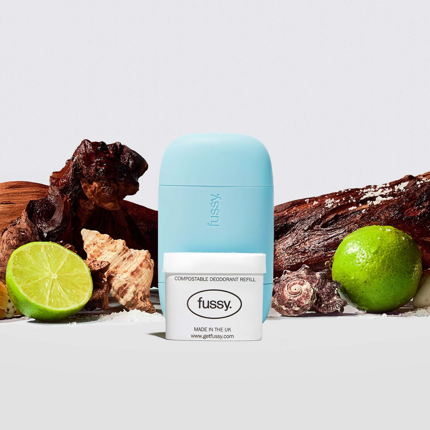 Fussy's All At Sea Starter Deodorant Pack featuring a Blue case and one refill pack set against a backdrop of cedarwood, limes and sea shells.