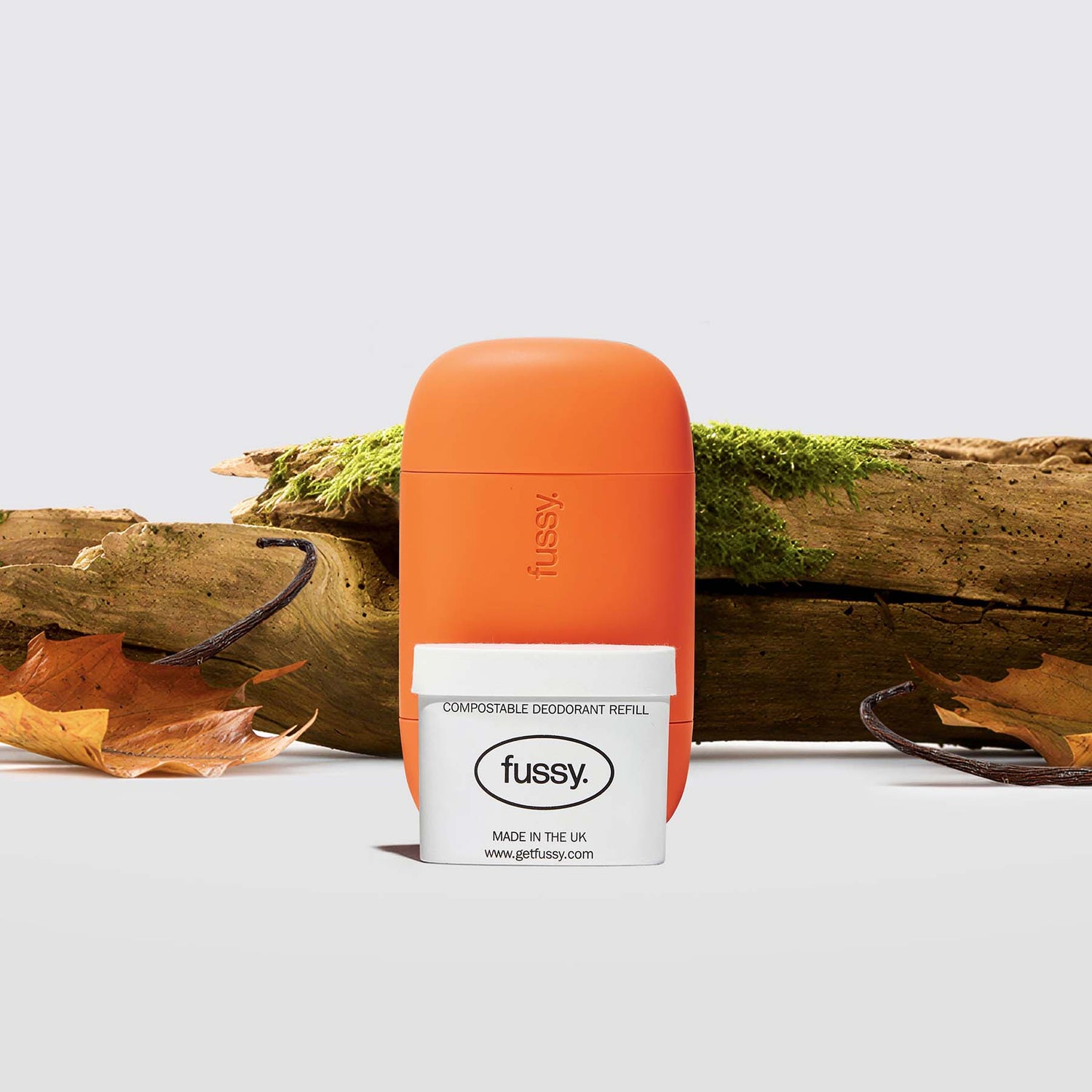 Fussy's Road Trip Deodorant Starter Pack featuring a Burnt Orange case and one refill pack set against a backdrop of moss-covered sandalwood and tonka bean pods.